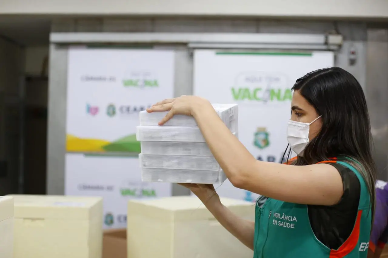 profissional segura caixa com doses da pfizer