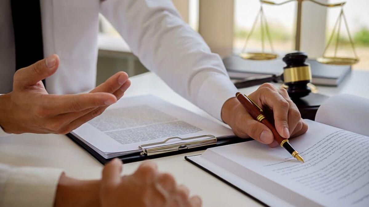 mãos de pessoa segurando caneta e gesticulando em cima de papéis