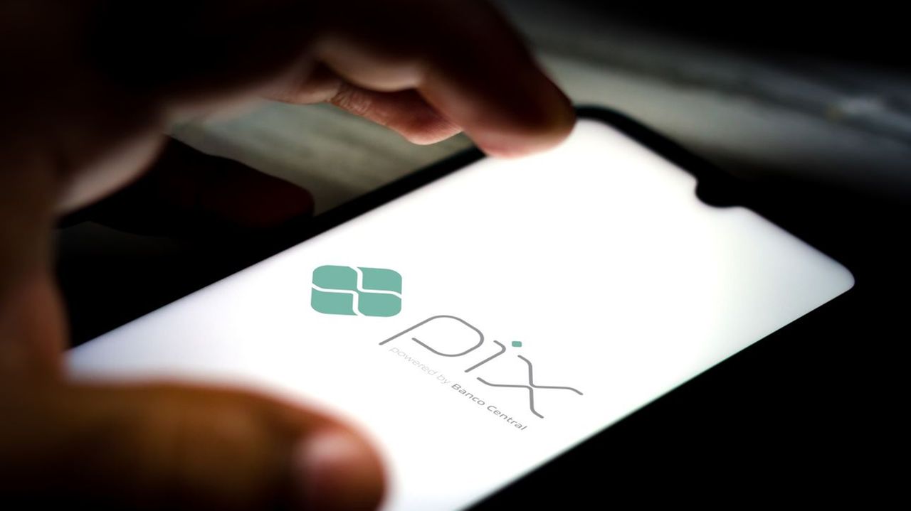 Mão sobre celular com logo do Pix na tela