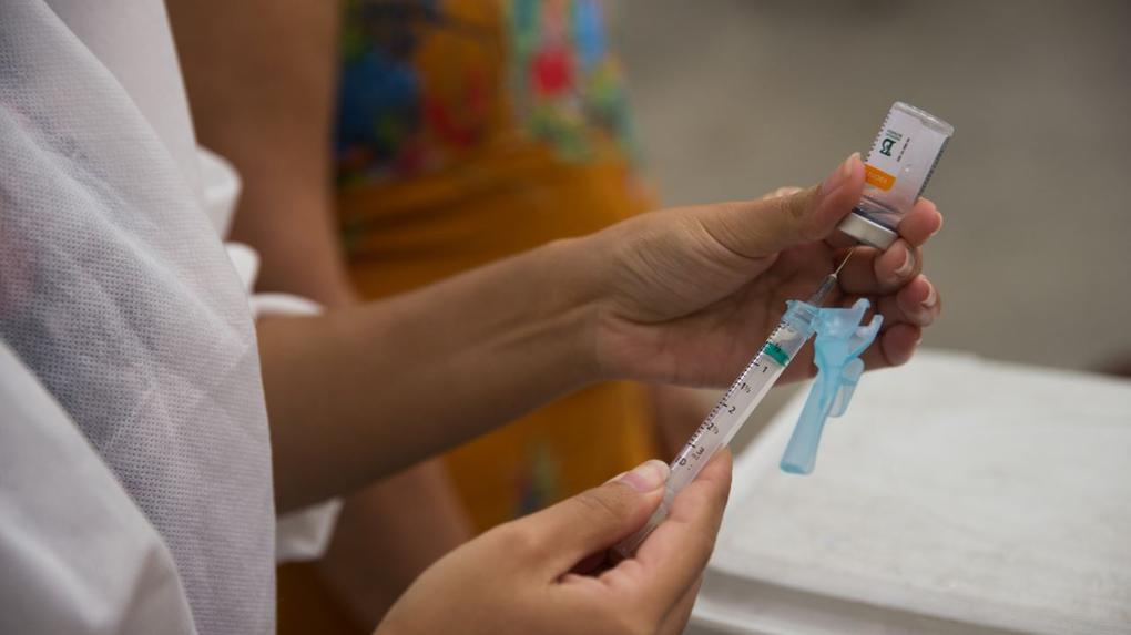 profissional de saúde insere dose de vacina em seringa