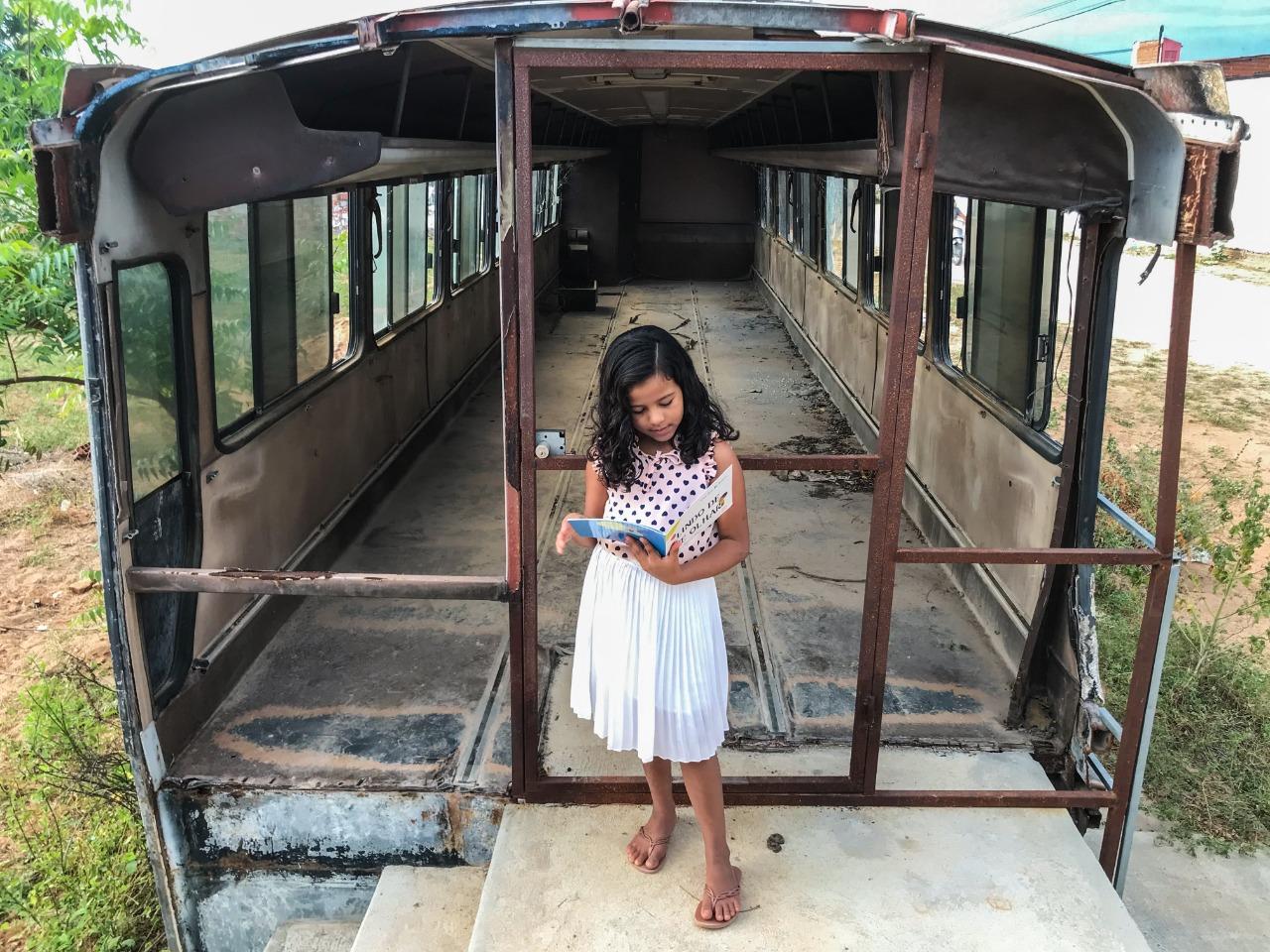 Ana Lívia, 7 anos, lê dentro do onibus-sucata na comunidade de Espinho - Limoeiro do Norte