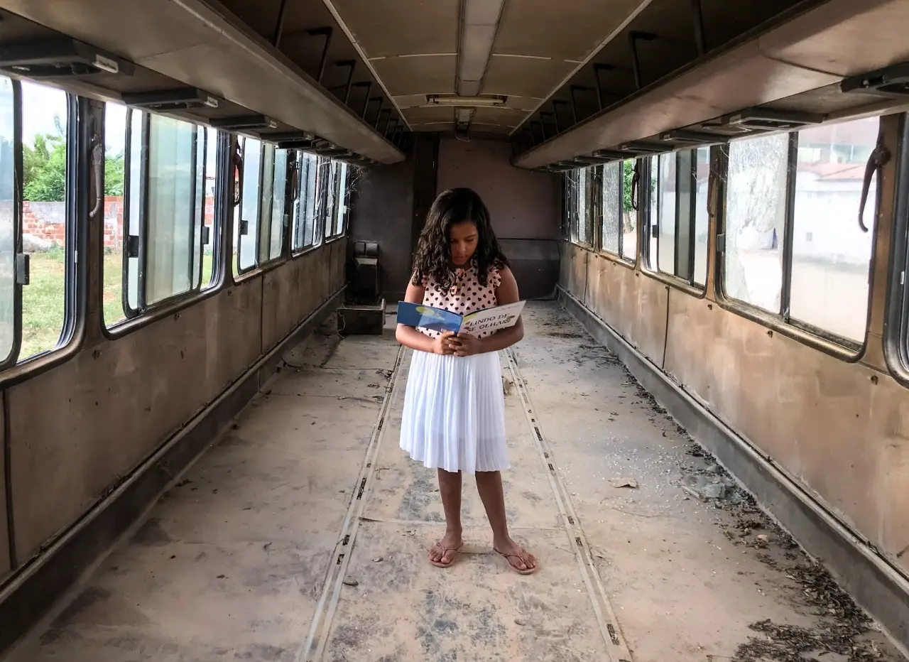 Ana Lívia, 7 anos, lê dentro do onibus-sucata na comunidade de Espinho - Limoeiro do Norte