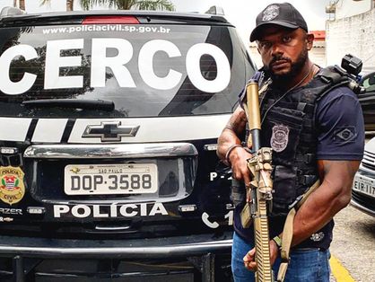 Delegado da Cunha segurando metralhadora perto de viatura
