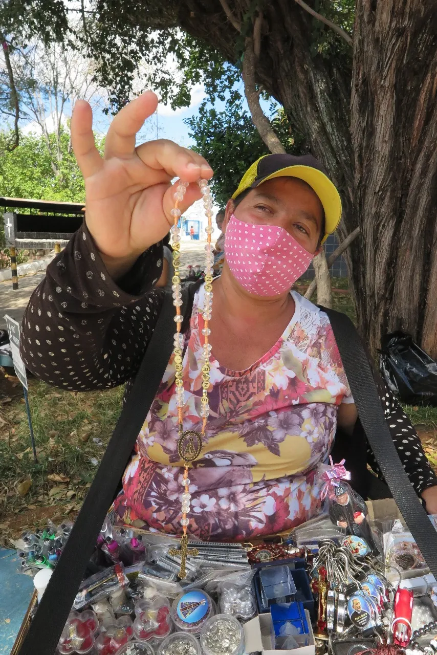 Regina Santos começou a vender ao lado do monumento do fundador da cidade, a partir dos 13 anos de idade, oferecendo velas aos romeiros