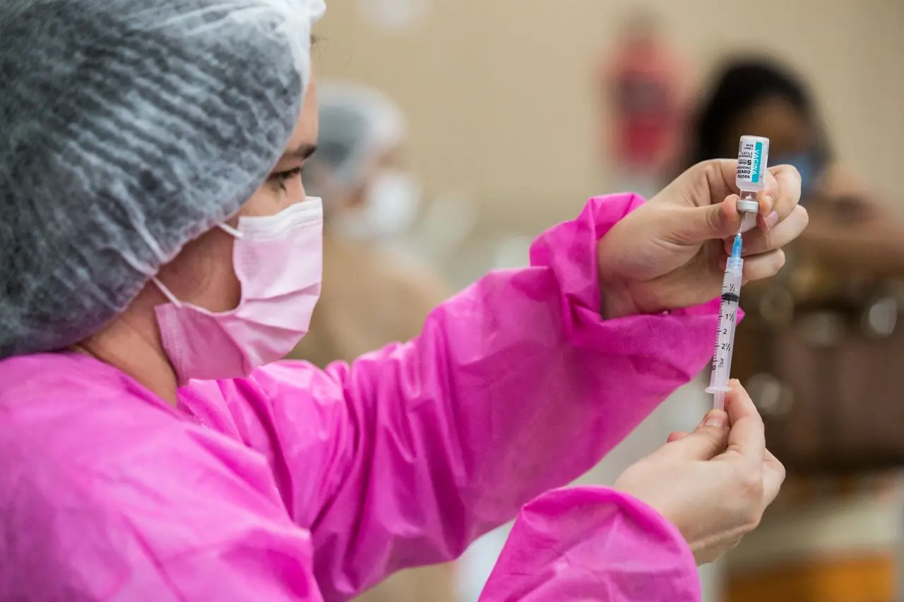 profissional coloca dose de vacina contra a covid-19 em seringa