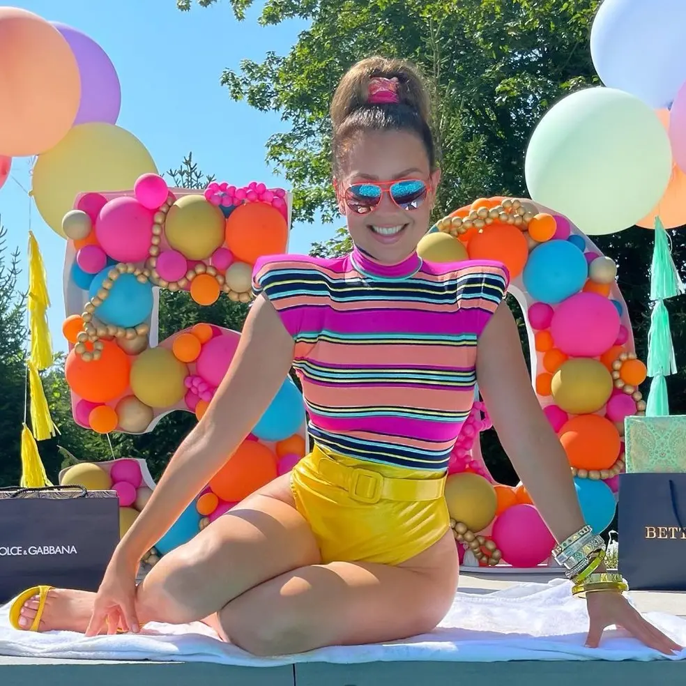 Thalia sentada em frente a letreiro com número 50