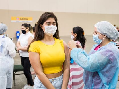 Adolescente de camisa amarela sendo vacinada contra a Covid-19 no Centro de Eventos, em Fortaleza