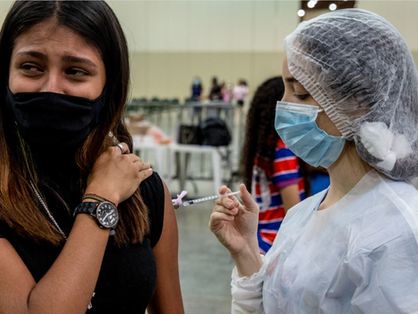 Enfermeira aplicando vacina contra Covid-19 em adolescente