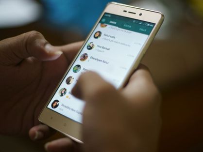 Mão segurando celular com lista de conversas no WhatsApp