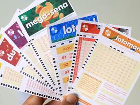Bilhetes de loteria formando um leque na mão de jogador, que recebe close