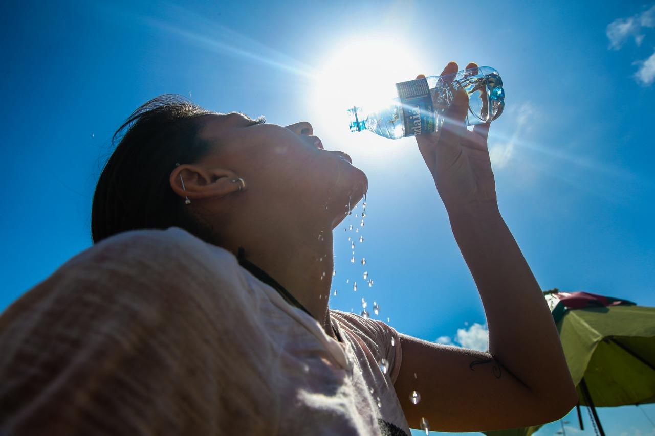 Mulher bebendo água sob forte calor