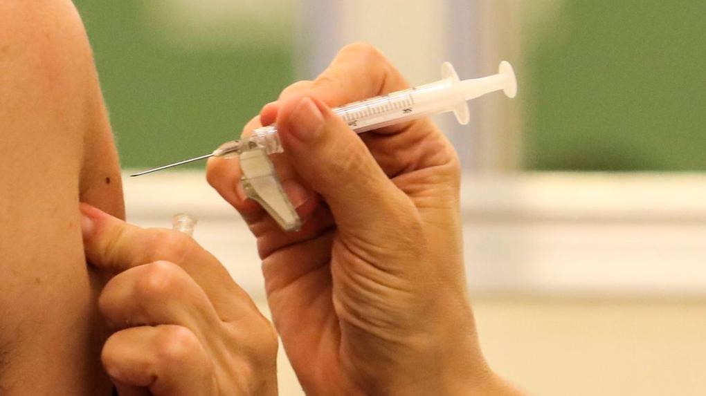 Close no braço de uma mulher que está prestes a receber a agulhada da vacina