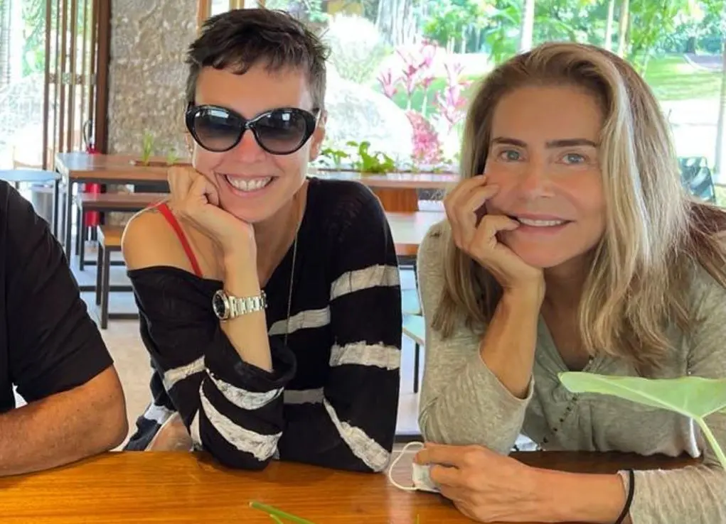 Adriana Calcanhotto ao lado de Maitê Proença, ambas com queixo apoiados sobre mãos direitas