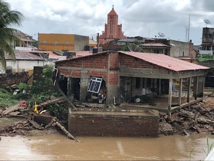 Foto de moradia com parte da frente destruída, durante chuva