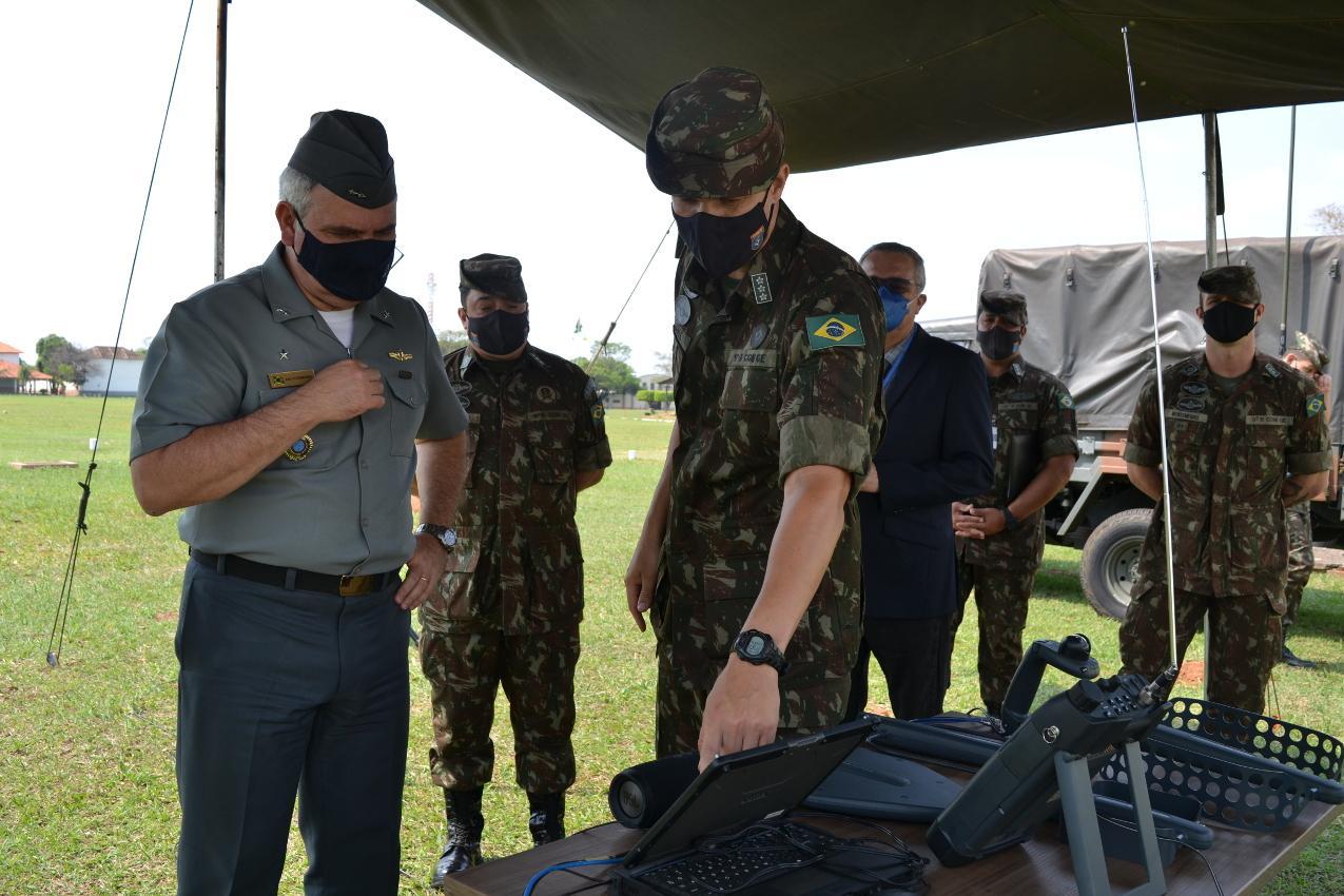 Militares vestidos em roupas institucionais analisando computador
