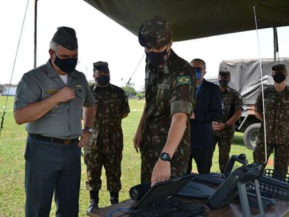 Militares vestidos em roupas institucionais analisando computador