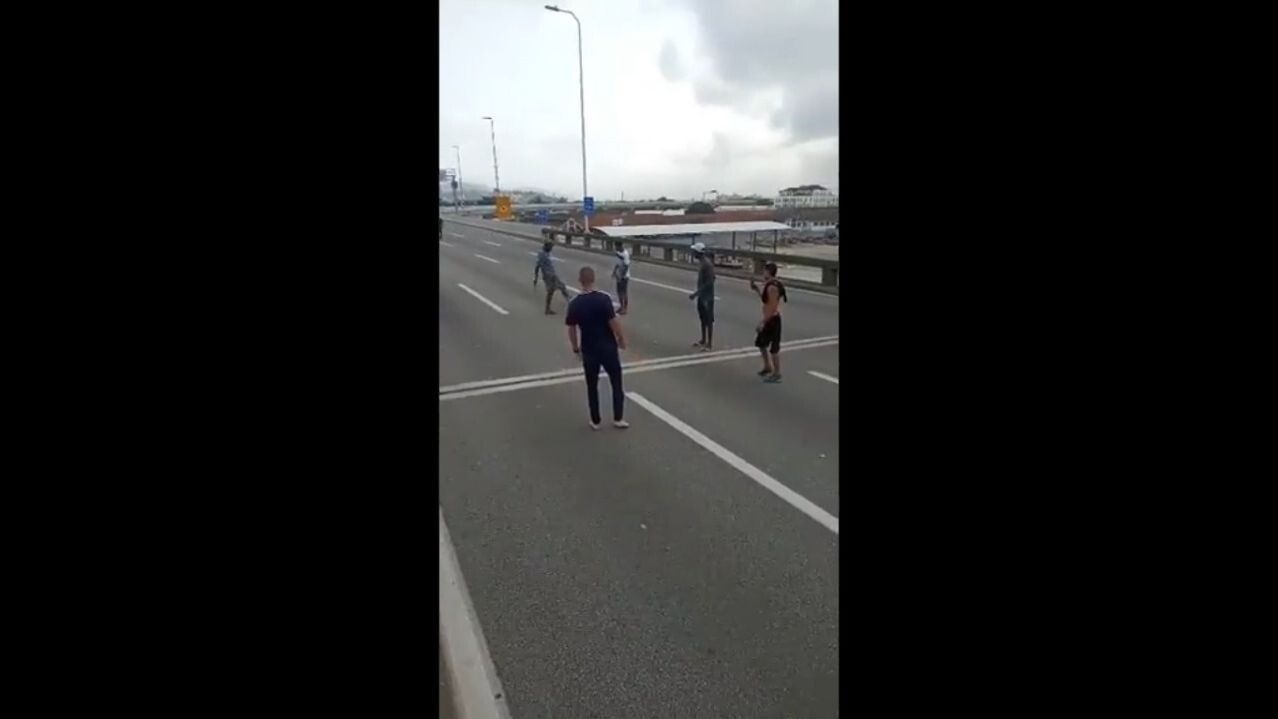 Pessoas jogando bola enquanto o trânsito está parado