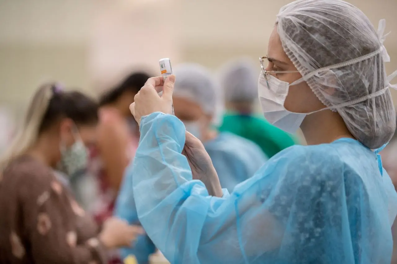 profissional de saúde injeta dose de vacina contra a covid-19 em seringa