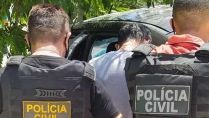 Imagem mostra dois policiais civis com fardas da instituição prendendo um homem