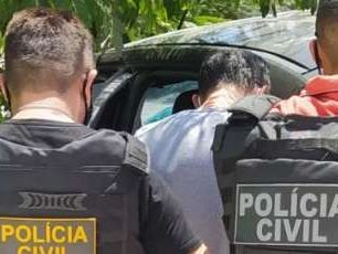 Imagem mostra dois policiais civis com fardas da instituição prendendo um homem