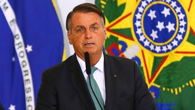Presidente Jair Bolsonaro testa negativo para Covid. Na imagem, ele aparece à frente de uma bandeira do Brasil