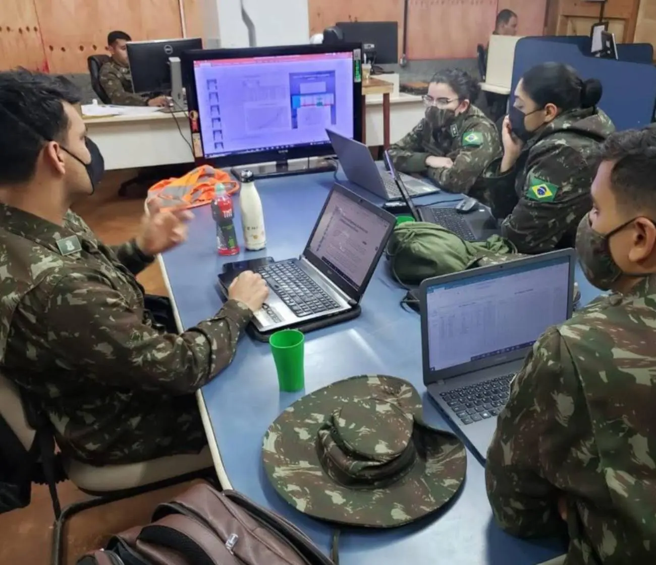Homens e mulheres com fardas do Exército ao redor de mesa