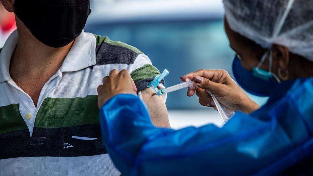 Profissional de saúde aplicando vacina no braço de homem