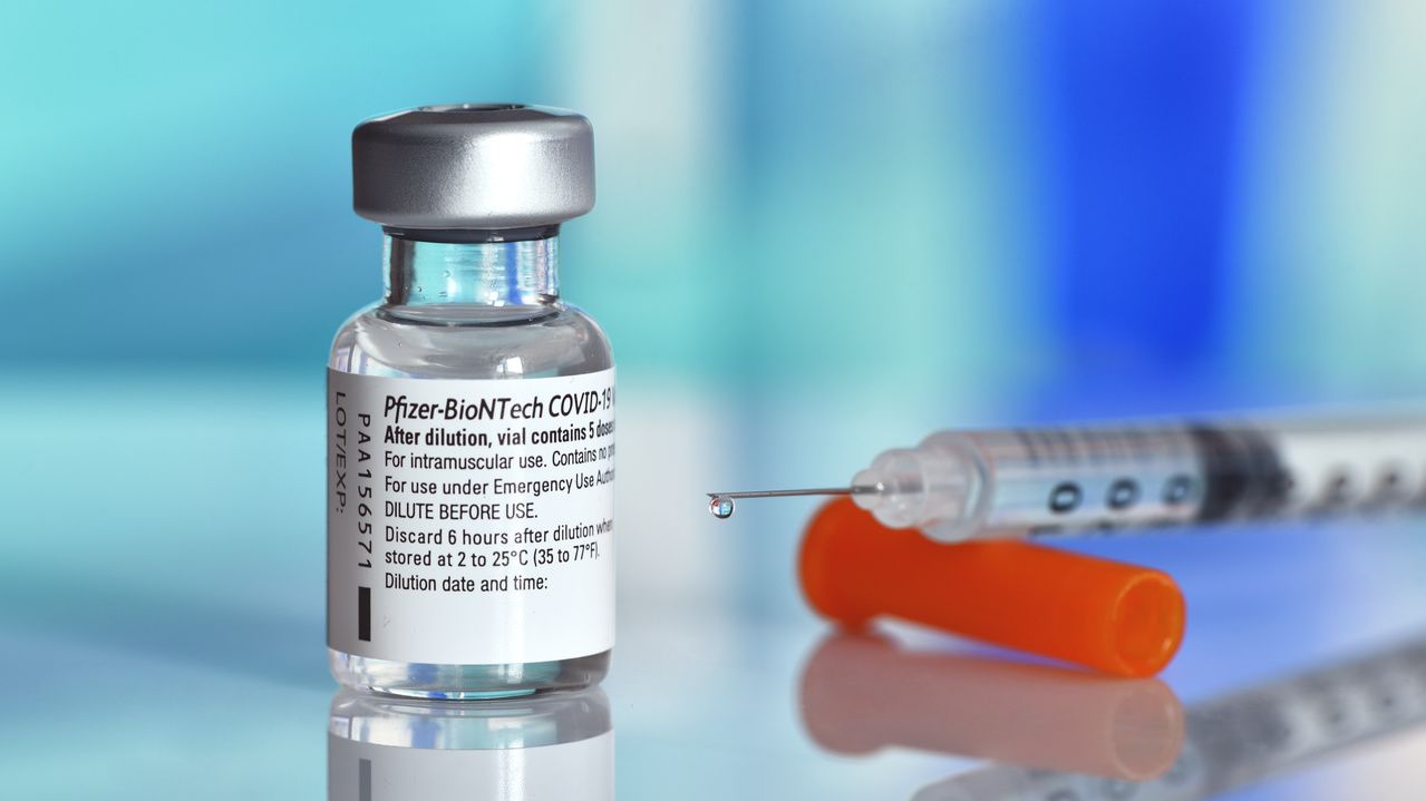 Frasco com imunizante da Pfizer cheio e injeção carregada ao lado