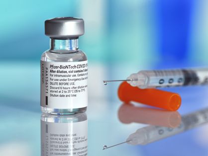 Frasco com imunizante da Pfizer cheio e injeção carregada ao lado