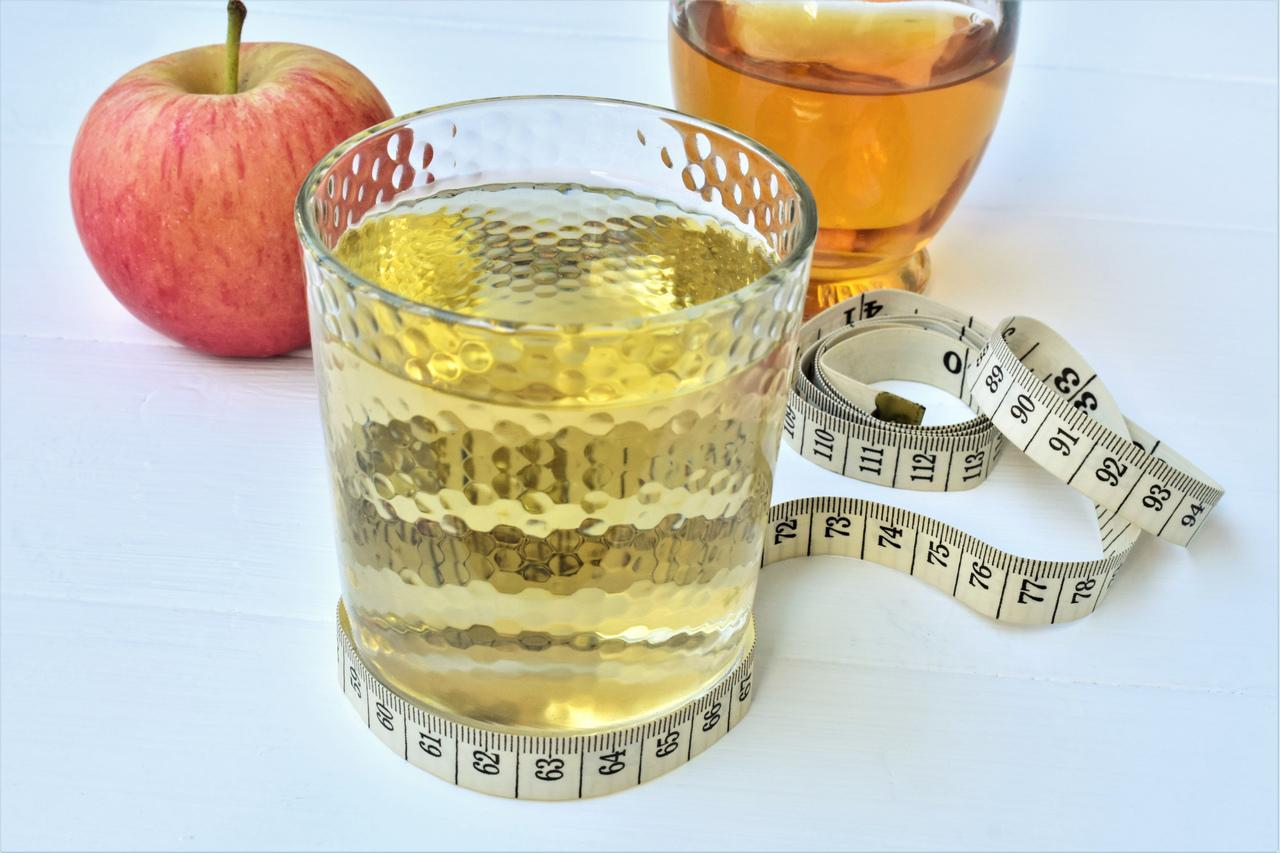 Maçã ao lado de um copo com vinagre de maçã e envolvido por uma fita métrica