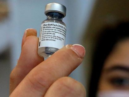 Mulher segurando fraco com a vacina contra a Covid-19 desenvolvida pela Pfizer com a BioNTech