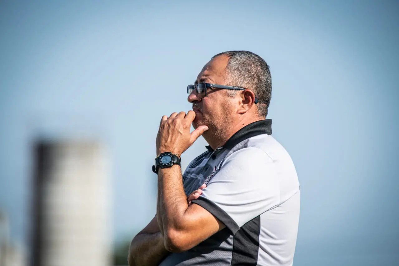 Raimundinho com a mão no queixo à beira do gramado