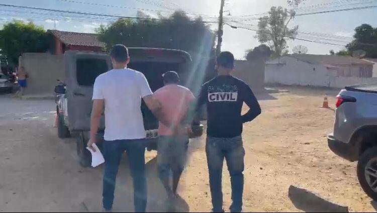 Homem preso por dois policiais civis sendo levado para viatura