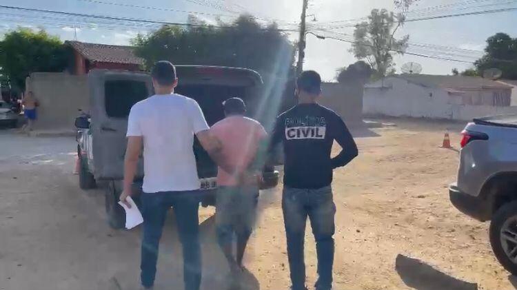 Homem preso por dois policiais civis sendo levado para viatura