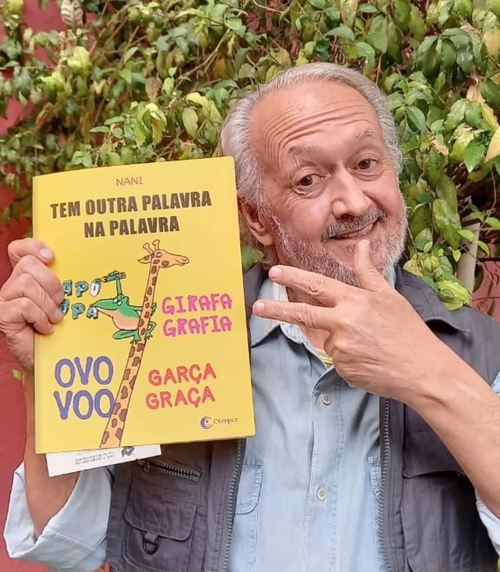 Nani segura um livro e sorri para a foto