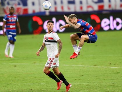Lucas Crispim sobe e cabeceia bola, sendo observado pro jogador do São Paulo