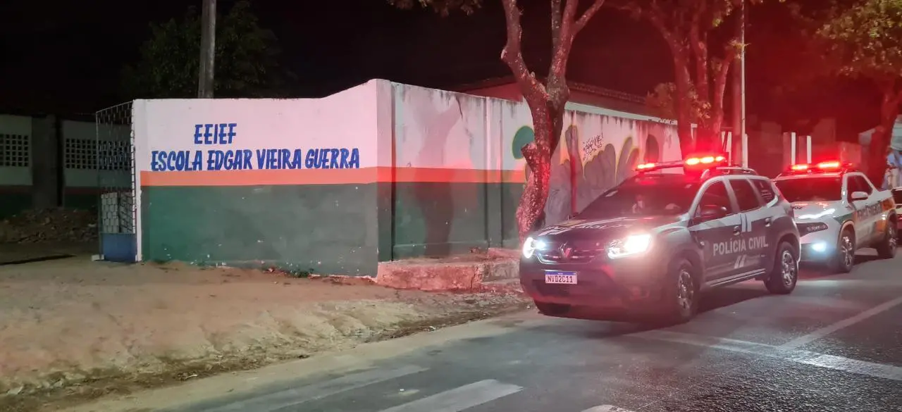 Imagem mostra carros da Polícia Civil e da Perícia Forense estacionados em frente à Escola Edgar Vieira Guerra, em Caucaia, no Ceará