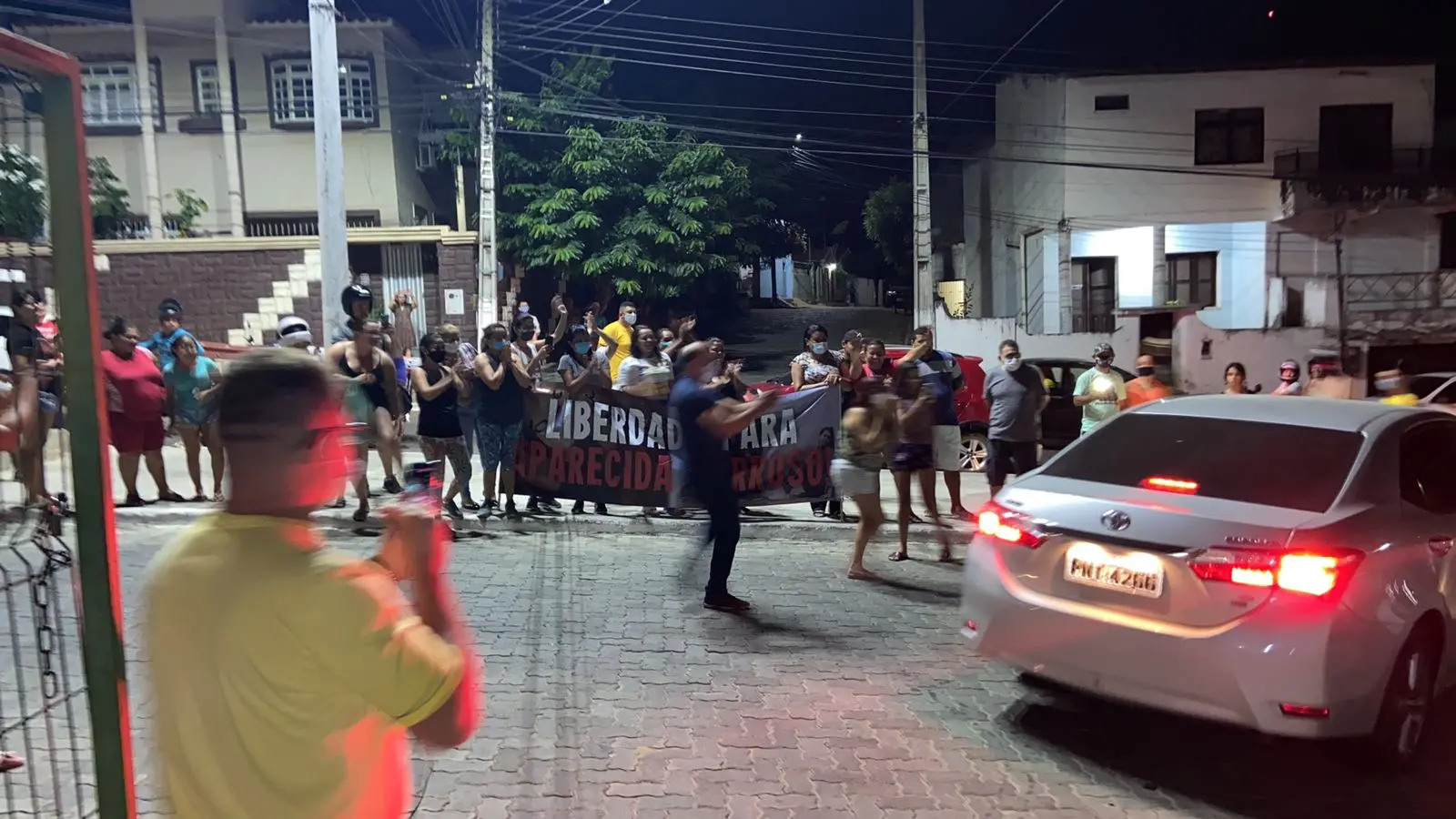 Populares aguardando a saída de Maria Aparecida da prisão, segurando cartazes de apoio