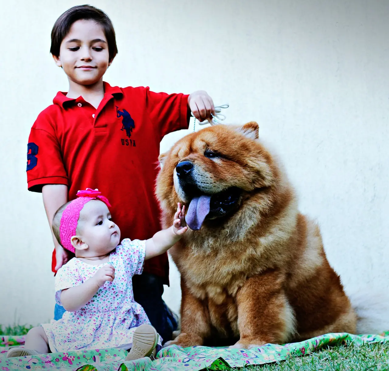 Eros fotografado ao lado de um menino e uma bebê, que encosta a mão em sua língua