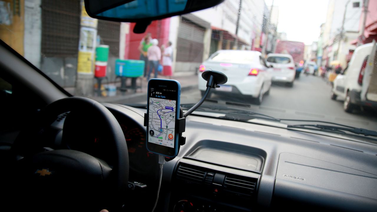 Carro parado no trânsito, com celular posicionado no vidro do carro
