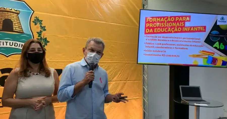 Na imagem, estão a secretária da Educação de Fortaleza, Dalila Saldanha, à esquerda, e o prefeito José Sarto, à direita. Os dois estão de máscara ao lado de um painel com dados sobre a rede municipal.