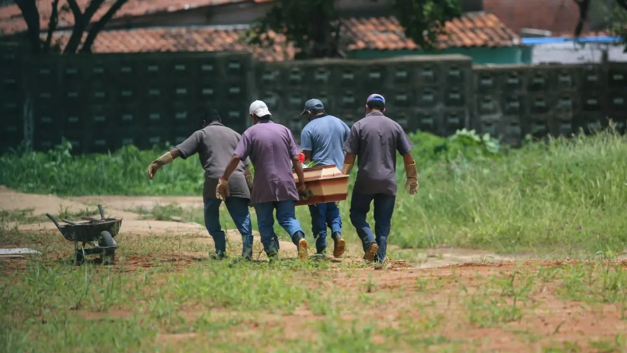 Coveiros carregando caixão em cemitério do Ceará