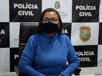 A advogada, vítima responsável por denunciar caso de racismo em uma loja da Zara, sentada à frente de um painel da Polícia Civil