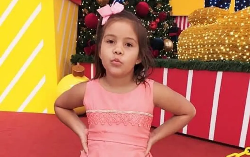 A imagem mostra a vítima do esmagamento, uma menina de 8 anos em um vestido rosa e com um laço da mesma cor no cabelo.