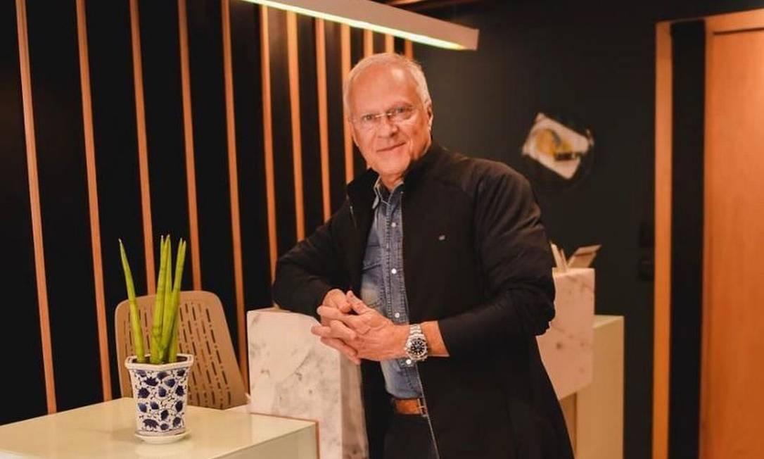 Médico posando para a foto encostado em uma mesa