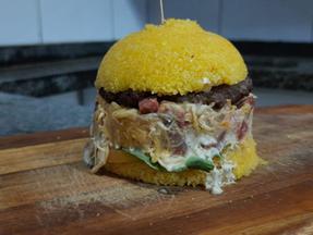 Hambúrguer de cuscuz cortado no formato de pão bola e recheado em cima de uma tábua
