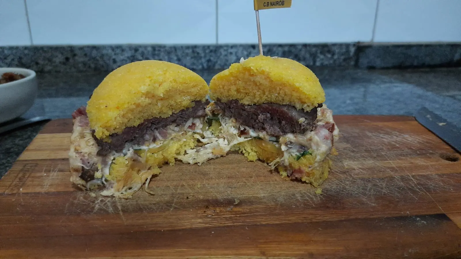 Hamburguer de cuscuz cortado ao meio, revelando todas as camadas de recheio