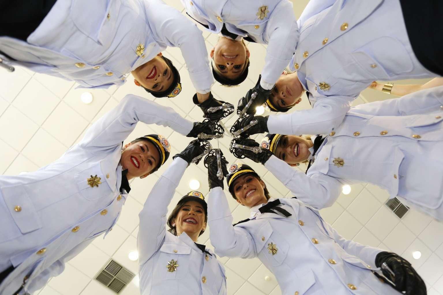 Vistas de baixo para cima, um grupo de Militares mulheres levantam espadins
