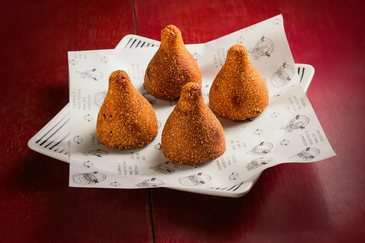 Quatro coxinhas com massa de cuscuz, fotografas sobre guardanapo personalizado