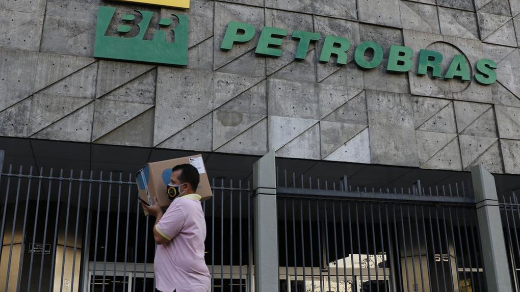 Homem carregando caixa passando em frente à fachada da Petrobras